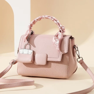 Pink patchwork handbag with scarf handle and woven texture detail in a soft scene