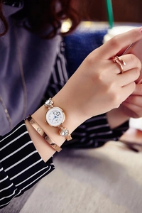 Detail of gold quartz watch with rhinestone flowers and polished metal bracelet