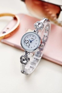 Detail of silver ladies watch featuring flower crystals and double heart dial design