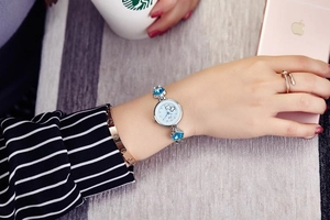Detail of silver ladies' watch with blue heart stones and sleek chain strap
