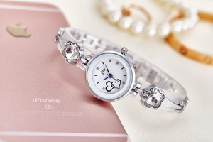 Detailed view of silver quartz bracelet watch with floral rhinestones and heart charms