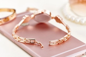 Detail of rose gold watch strap and clasp with luxury pearl jewelry and bracelet