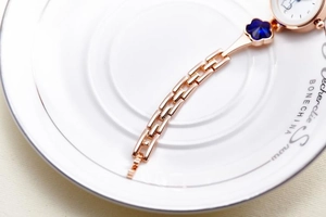 Macro shot of rose gold metal strap with deep blue crystal floral details on women watch