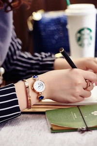 Elegant gold quartz watch with floral strap paired with a screw bangle and nail ring