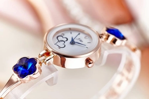 Detail of rose gold bracelet watch with blue flower crystals and heart dial design