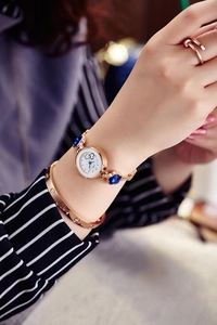 Detail of rose gold quartz watch featuring floral blue crystals on metal link bracelet