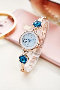 Detail of rose gold bracelet watch featuring blue floral crystals and double heart dial