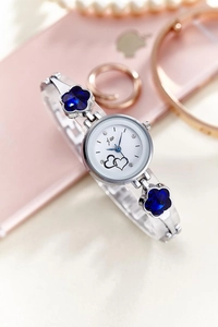 Close-up of silver-toned bangle watch with blue crystal flowers and white heart dial
