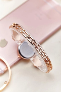 Macro detail of rose gold watch band with H-link design and textured finish