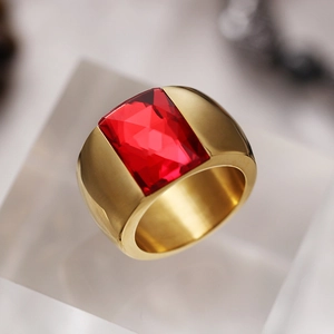 Macro view of gold plated wide band ring with a large rectangular red crystal on acrylic