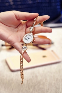 Close-up of rose gold watch with floral link strap and rhinestone heart dial detail