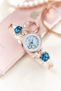 Detail of rose gold bracelet watch featuring blue crystal flowers and heart dial