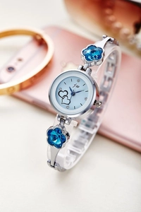 Close-up of silver watch with floral links, blue crystals and heart-shaped dial details