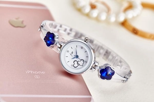 Close-up of quartz watch with white heart dial and blue floral crystal bracelet