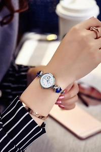 Close-up of women's quartz watch with silver steel band and blue clover charms