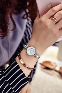 Close-up of heart-pattern quartz watch with crystal floral bracelet on woman's wrist