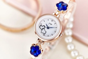 Close-up of rose gold watch dial with double heart pattern and blue flower rhinestones