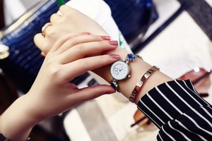 Close-up of women's silver quartz watch with blue heart gemstone and steel mesh strap