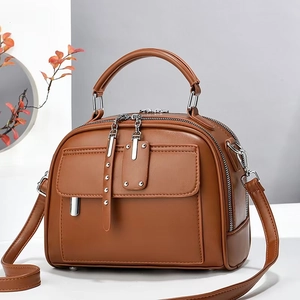 Detail view of large capacity brown leather crossbody bag with silver hardware and dual zippers