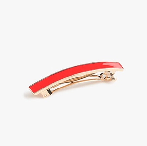 Detailed close-up of golden alloy spring hair clip with red rectangular enamel inlay
