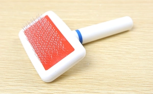 Detail of ergonomic pet slicker brush with fine metal needles for grooming loose fur