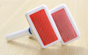 Close-up of pet grooming brush with stainless steel needles and anti-slip handle