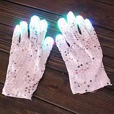 Macro detail of LED glowing sequin gloves with colorful light-up fingertips on dark wood