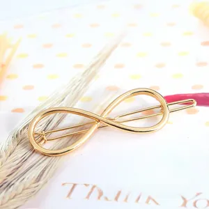 Close-up of a golden infinity symbol metal hair clip on a minimalist gift card background