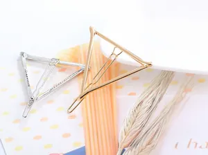 Close-up of geometric triangle metal hair clips in gold and silver finish with flat lay props
