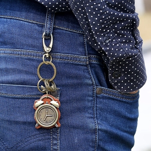 Vintage bronze alarm clock keychain on leather strap attached to denim jeans loop