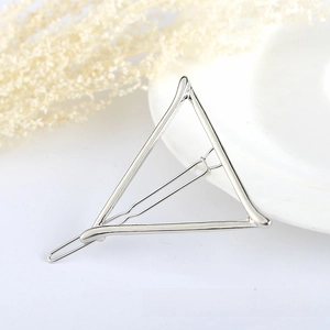 Detailed view of a silver geometric triangle hair clip on a minimalist white surface