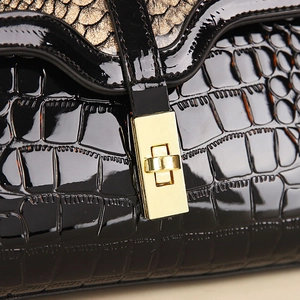 Macro shot of black patent leather bag with crocodile pattern and golden metal turn lock