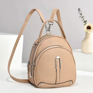 Detail view of beige lychee texture backpack with triple zipper compartments and silver hardware