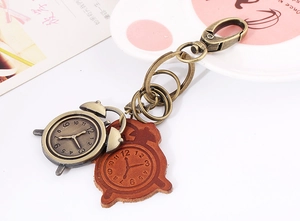 Macro view of vintage bronze alarm clock pendant and embossed leather keychain detail