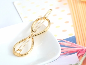 Close-up of golden infinity shaped metal hair clip with a polished finish for women