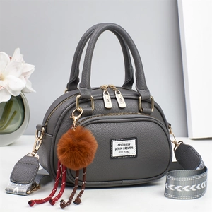 Detail der grauen Lederhandbagge mit Muschelform und gewebtem Jacquard-Schultergurt
