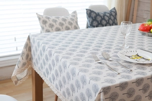 Detailed view of beige linen tablecloth with grey tree patterns and elegant lace borders