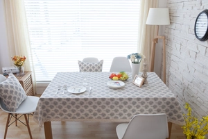 Detail of beige tablecloth with grey tree patterns and elegant lace trim on a wood table