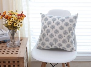 Close-up of modern linen cushion with minimalist grey tree pattern on a white chair