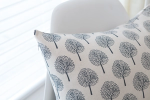 Detailed view of beige linen cushion cover with grey tree pattern and zipper closure