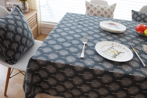 Detail of dark grey linen tablecloth and pillow with white tree patterns in a cozy room