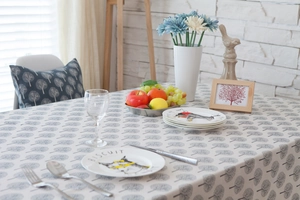 Detailed setting of tablecloth with grey tree patterns and illustrated ceramic plates