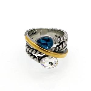 Dettaglio dell'anello a cavo bicolore con pietra blu a goccia e cristallo ovale
