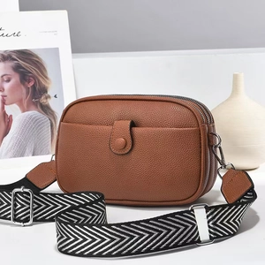 Brown lychee leather crossbody bag with three zippers and stylish wide geometric strap