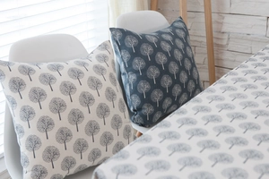 Detailed view of linen cushions and tablecloth featuring elegant tree pattern prints