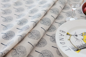 Detail of linen tablecloth with grey tree patterns featuring elegant beige fabric drape