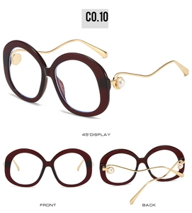 Macro detail of wine red round sunglasses featuring gold wavy temples and pearl accents