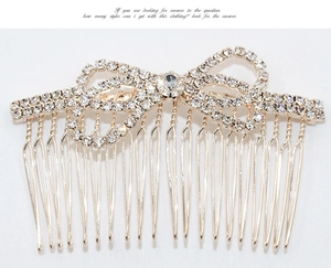 Close-up of golden hair comb featuring a sparkling rhinestone bow design on white background