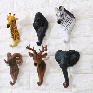 Dettaglio di sei ganci decorativi a testa di animale su una parete di mattoni bianchi