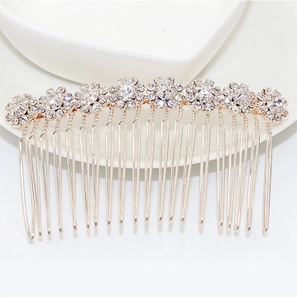 Detail of a golden metal hair comb with sparkling rhinestones on a white ceramic dish